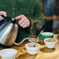 man-pouring-boiling-water-into-coffee-bowls-for-ta-2025-04-03-16-55-23-utc.webp